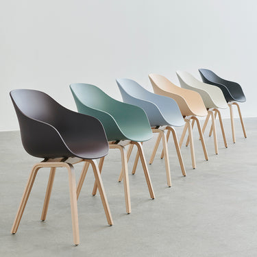 A row of AAC 222 chairs with wooden legs and molded plastic seats in various colors.