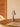 Table lamp on a wooden table with an open book and a glass of water, against a beige wall.