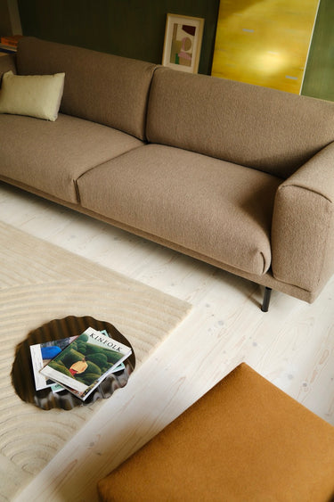 Interior image of a 3.5 seater rest sofa upholstered in taupe boucle fabric in a warmly lit room.