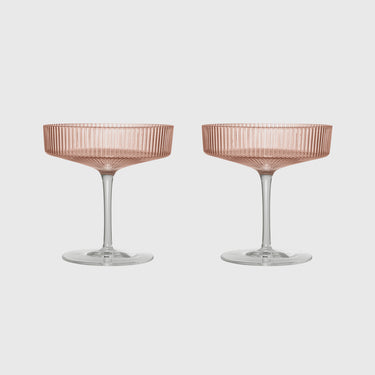 Two rose gold champagne coupe glasses with a ribbed pattern on the bowl and clear stems, set against a light gray background.