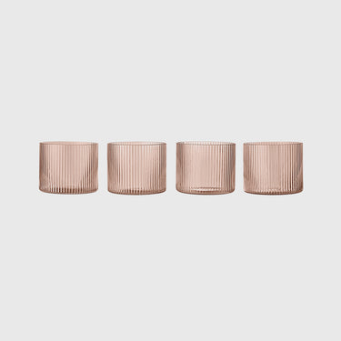 Four ribbed glass tumblers in a translucent dusty rose pink color, arranged in a row against a light gray background.