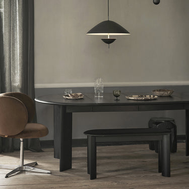 Interior image of a black extendable table with matching bench in an interior room with a pendant and dining chair.