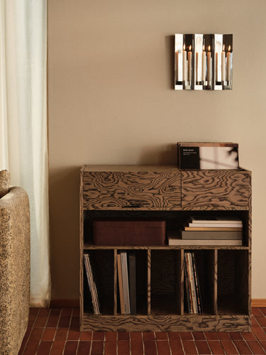 A dark brown wooden record store cabinet with a distinctive wavy woodgrain pattern, styled with vinyl records and books in a warm-toned room.