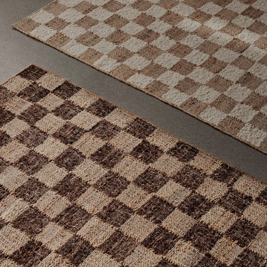 Detailed image of two woven checkered rug on a dark grey floor.