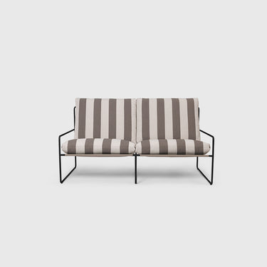 A two-seater outdoor sofa with striped black and chocolate cushions, featuring a steel frame, placed on a outdoor setting with plants in the background.