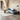 A modern curved light blue sofa with a brown accent pillow in a rustic stone-walled room with arched ceilings, a white rug, and a black floor lamp.