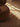 Brown textured ottoman on a wooden floor with sunlight casting shadows