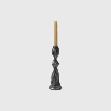 A black, recycled cast aluminum Gale Candle Holder with a swirling, organic shape featuring a candle.