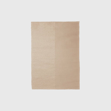 A rectangular area rug in a light beige color, featuring a subtle vertical ribbed texture, shown flat against a neutral light gray background.