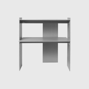 A minimalist two-tier desk with a modern industrial design, featuring a matte gray finish and a central vertical support panel, shown against a light gray background.