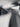 Close-up abstract view of a ribbed cylindrical product in grayscale, with shallow depth of field and blurred background shapes.