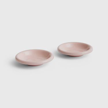 Two small shallow round dishes in a dusty pink color, shown on a light gray background.