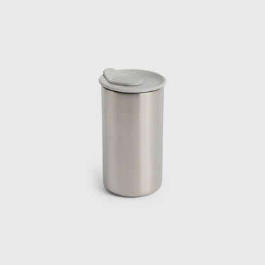 Silver cylindrical container with a lid on a light gray background