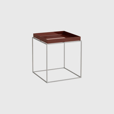 A modern side table featuring a dark brown rectangular tray on top of a minimalist open cube frame made of thin silver metal tubes, set against a solid light gray background.
