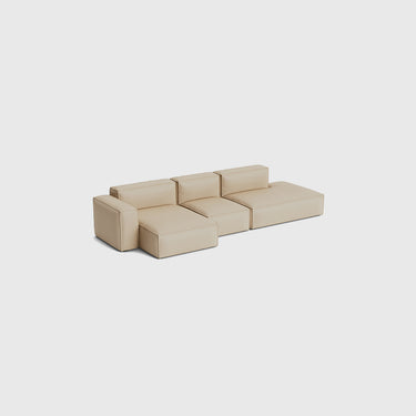 A modular low-profile sectional sofa upholstered in a light beige fabric, shown from a high-angle perspective against a solid light grey background.