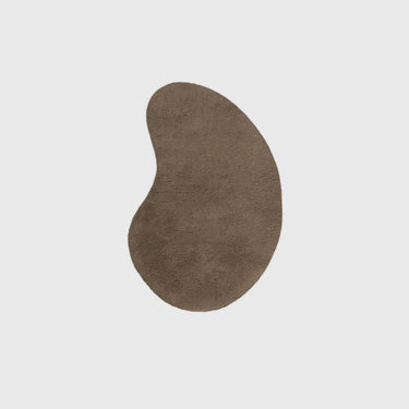 An organic-shaped, bean-like area rug in a warm taupe-brown color, shown from a top-down view on a solid light gray background.