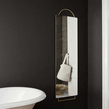 Minimalist wall mirror on a black wall in a bathroom.