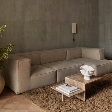 Coffee table in a living setting with a sofa in the background, a shaggy rug and a grey wall.