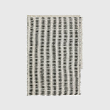 Flat rug with woven line design on a light grey background.
