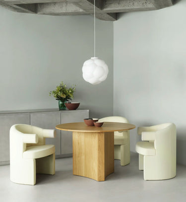 Modern dining area with a wooden table and cream chairs in a minimalistic setting.