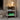 White metal shelf with a lamp, books, and a green box against a textured wall.