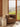 Brown armchair in a room with a large window showing a scenic view of green fields and mountains.