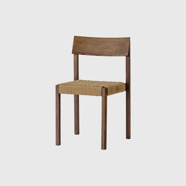 A modern wooden dining chair with a medium brown wood frame and a woven natural fiber seat, shown against a solid light grey background.