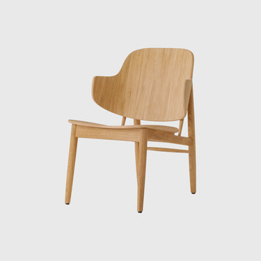 A modern wooden armchair with a curved backrest and tapered legs, made from light natural oak wood, shown against a solid light grey background.
