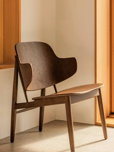 Wooden chair with a curved backrest and seat in a minimalistic setting.