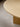 Close-up of a light oak wood oval table top with a matching wooden pedestal base on a neutral concrete floor.