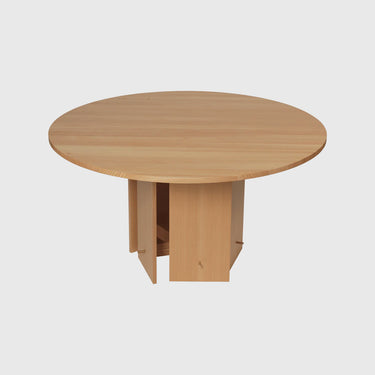 A round dining table made of oiled solid Douglas fir with a flat-packed construction and a brass hooks base, veneer with MDF core.