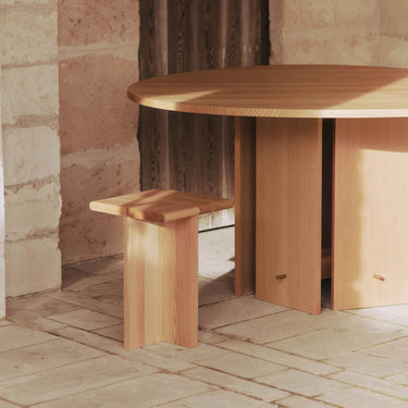 A round dining table made of oiled solid Douglas fir with a flat-packed construction and a brass hooks base, veneer with MDF core.