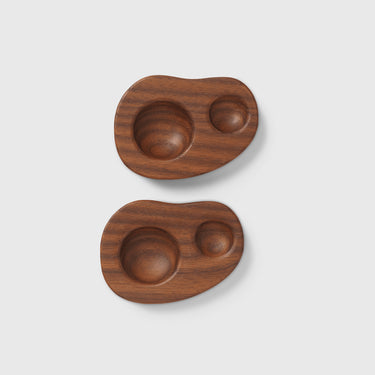 Two wooden trays with rounded edges and embedded circular indentations on a light gray background