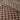 Detailed image of two woven checkered rug on a dark grey floor.