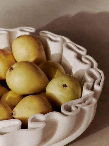 White ceramic bowl filled with pears on a beige background