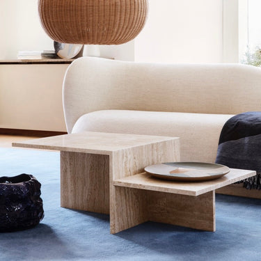 Interior coffee table in a living setting with a sofa, rug and rattan pendant.