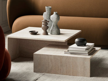 Interior image of a travertine coffee table with various sculptures in a livig room setting.