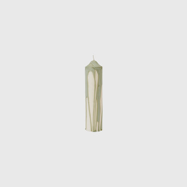 A single tall taper candle with a marbled pattern of sage green and cream, centered against a solid light gray background.