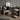 Interior image of a dark stained wood desk in a home office setting with a chair, table lamp and various desk decorative items. 