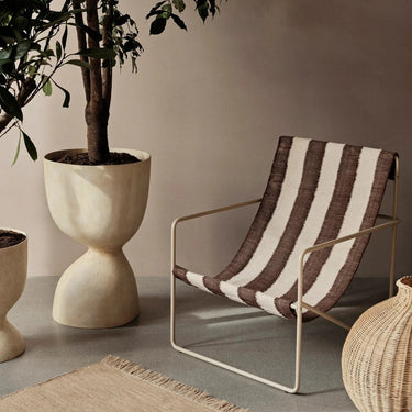Tall fiber stone pot suitable for indoor and outdoor use interior image with a striped outdoor lounge chair.