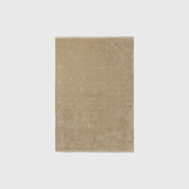 A rectangular beige rug with a soft, textured surface, centered on a light gray background.