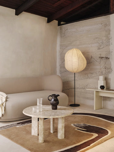 Modern living room with a beige sofa, marble table, and floor lamp.