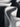 Abstract close-up of sculptural white curved objects with layered ridges, photographed in monochrome against a dark background.