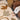 Person sitting on a brown couch next to a rug with abstract brown and beige designs.