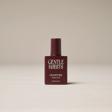 Perfume bottle labeled 'Gentle Habits Heartfire' on a beige background