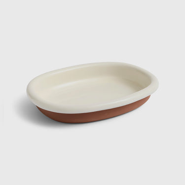 An oval ceramic dish with a glossy cream-colored interior and a matte terracotta brown exterior, shown on a light gray background.