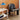 A black upholstered lounge chair with a smooth, streamlined design, positioned next to a white side table with a blue lamp on it, against an interior background.