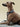 Dog wearing a striped harness on a striped cushion with a beige background