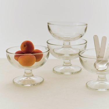Set of clear glass dessert bowls with fruit on a light background