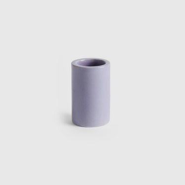 Purple cylindrical tooth brush holder on a light grey background